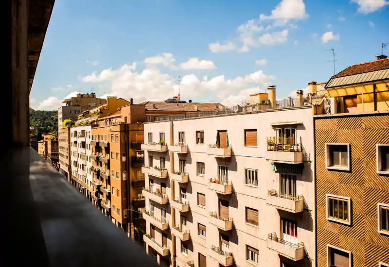 Vista dalla terrazza soleggiata sulle facciate di appartamenti cittadini, ideale per mostrare lo spazio esterno e l'atmosfera del quartiere.