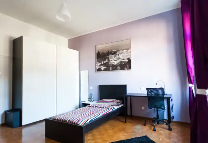 Bright, neatly styled single bedroom with a striped bed, desk and wardrobe; natural light and tasteful decor create a welcoming space ideal for a solo renter.