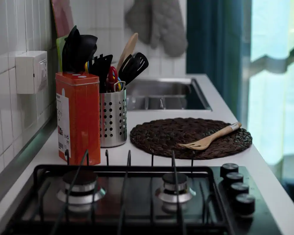 Plan de travail de cuisine compact et soigné avec plaque à gaz, porte-ustensiles et évier — propre et accueillant pour cuisiner.