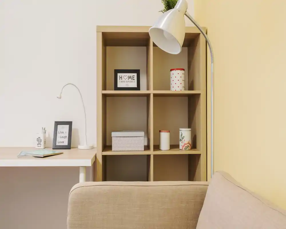Coin salon lumineux et chaleureux avec un canapé moelleux, une étagère et une lampe de lecture — bien rangé et invitant pour se détendre ou travailler.