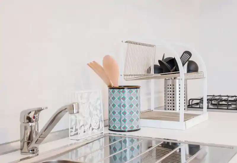 Zona lavello cucina luminosa e moderna con rubinetto in acciaio, portautensili e piano cottura vicino; stile pulito e minimale, ideale per annunci.