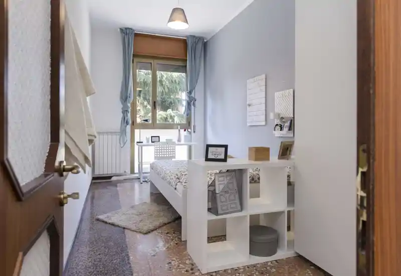 Bright, neatly styled single bedroom with a white bed frame, desk by the window and soft decorative touches, ideal for a single tenant or student.