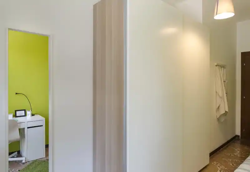 Entry corridor with built-in wardrobe and a view into a small room with a desk; neutral, well-lit hallway suitable for a listing emphasizing storage and access to adjacent rooms.