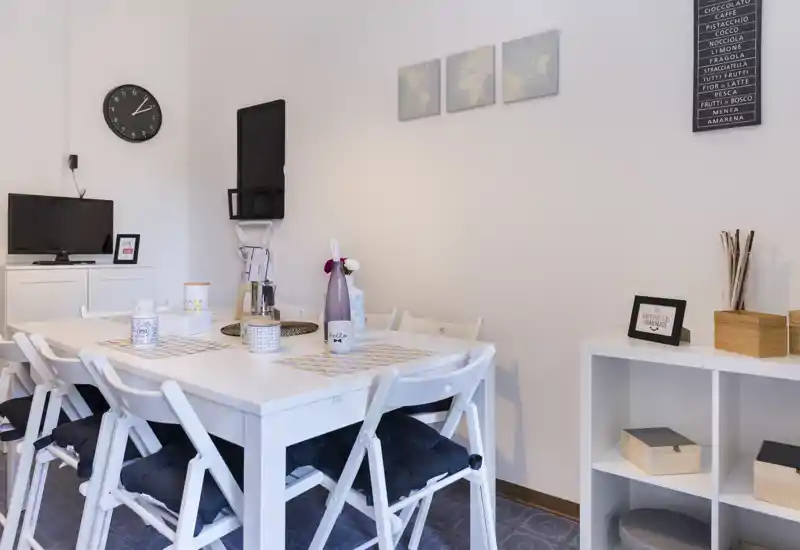 Bright, modern dining area with a white table and cushioned folding chairs, simple décor and organized storage — ideal for casual meals and small group dining.