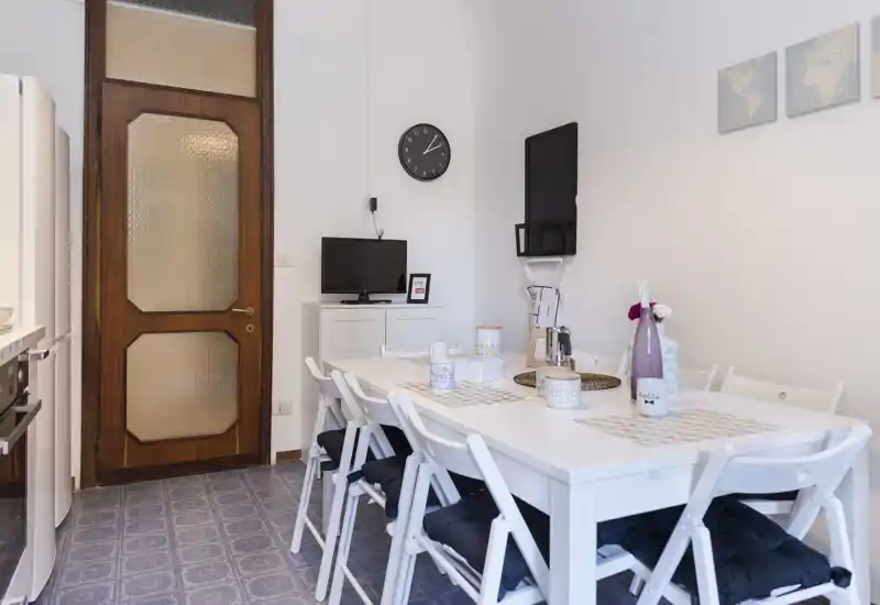 Bright, neatly styled dining area with a white table set for six, decorative placemats and vases — ideal for listing a rental's shared eating space.