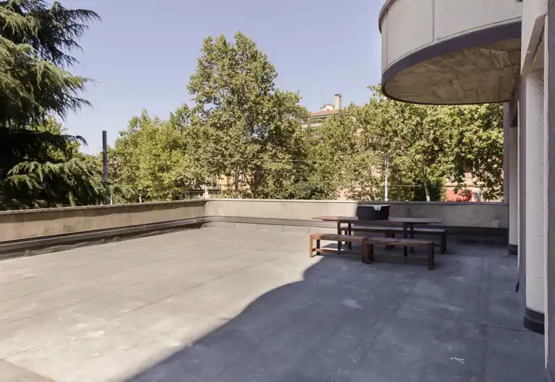Spacious private terrace with outdoor seating and pleasant city views framed by mature trees — ideal for relaxing or al fresco dining in daylight.
