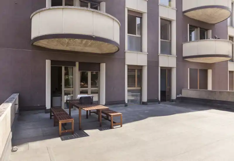 Spacious private terrace with a wooden dining set, concrete flooring and direct access from the apartment — ideal for outdoor meals and relaxation.