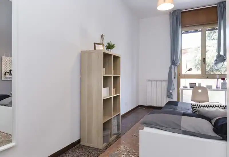 Chambre lumineuse et soignée avec un lit simple moderne, des textiles doux et un bureau près de la fenêtre apportant la lumière naturelle.