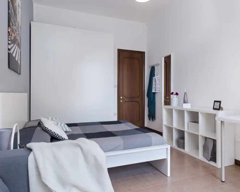 Chambre lumineuse et soignée avec lit double, placard encastré et étagères ouvertes ; tons neutres et décoration épurée, idéale pour une annonce.