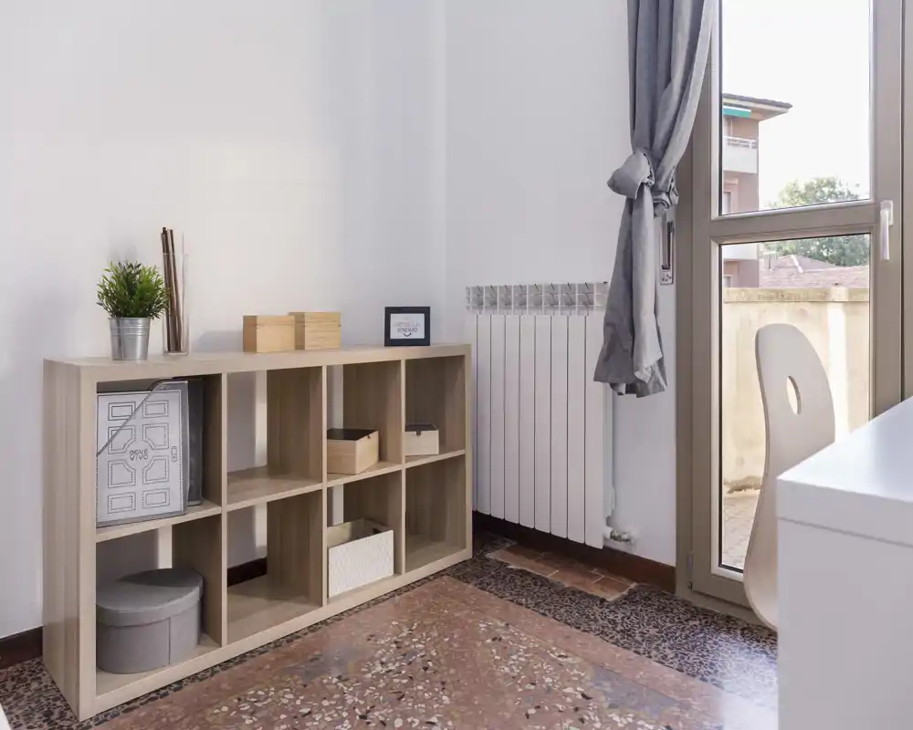 Espace de vie lumineux et minimaliste avec un meuble bas en cubes, boîtes décoratives et une fenêtre apportant la lumière naturelle — pièce calme et ordonnée, idéale pour un coin détente ou un bureau.