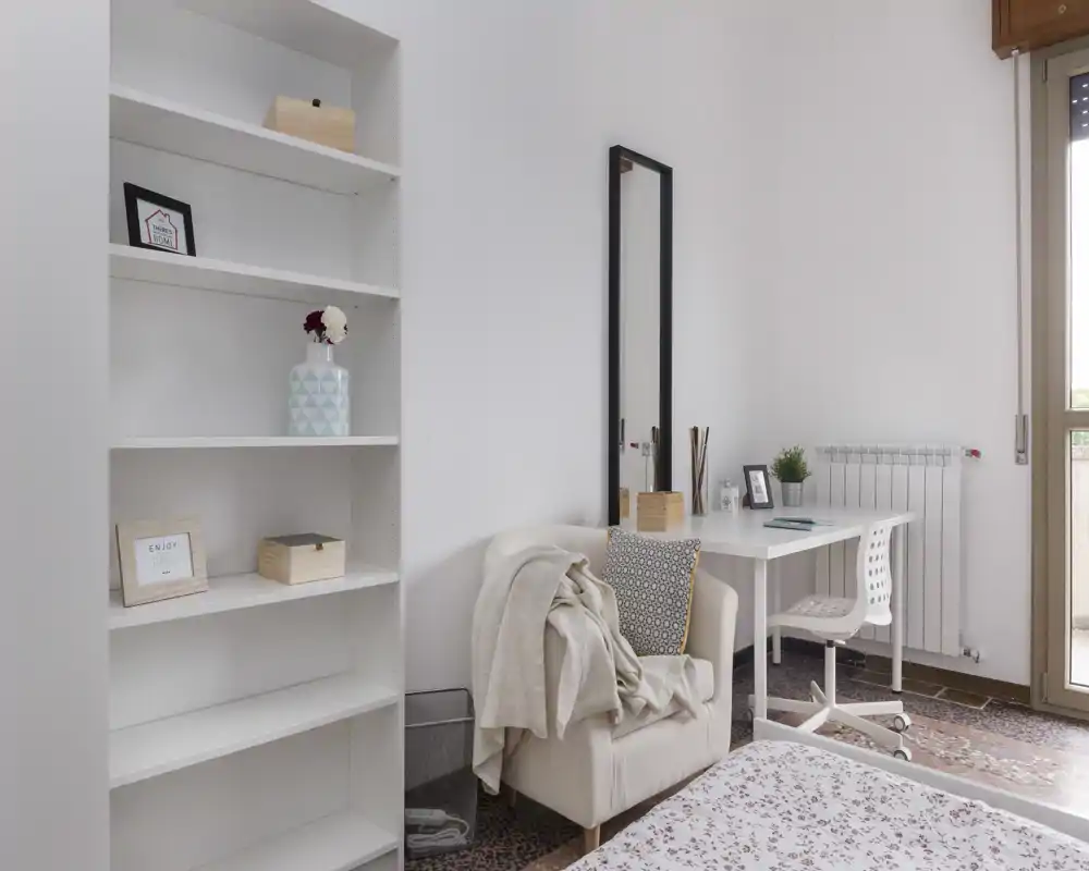 Bright, minimal bedroom corner with a visible bed, cozy armchair and a small desk by the window — ideal for work and rest.