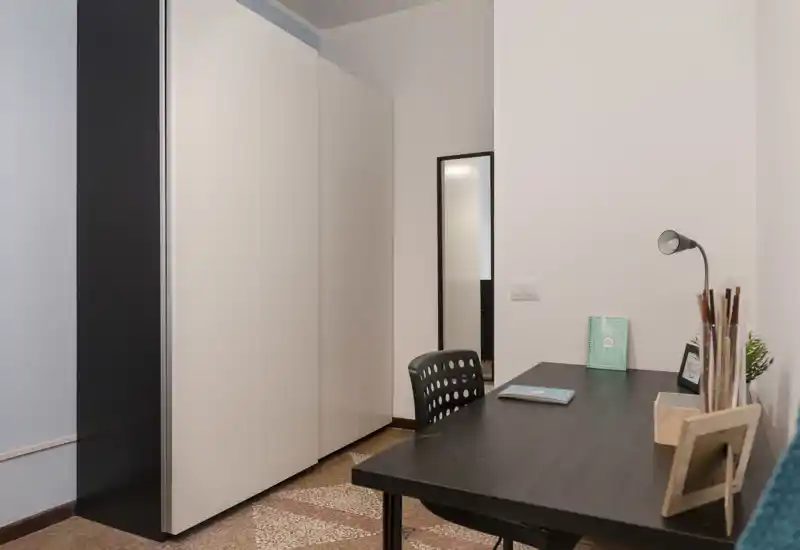 Coin chambre compact avec une grande armoire et un bureau fonctionnel ; lignes modernes et épurées, idéal pour travailler et se reposer.