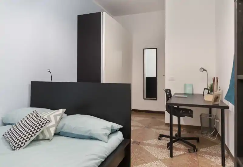 Chambre moderne et lumineuse avec un grand lit, coussins décoratifs et un bureau pratique — style minimaliste et carrelage à motifs apportant du caractère.