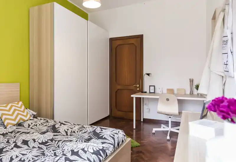 Camera da letto luminosa e ben arredata con letto con stampa, grande armadio e una scrivania: perfetta per soggiorni confortevoli e smart working.