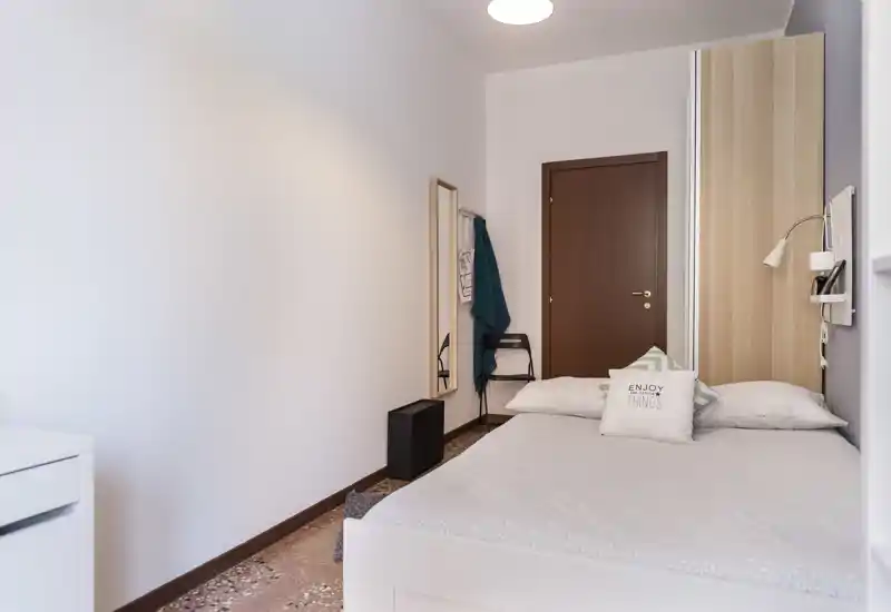 Bright, tidy single bedroom with a neatly made bed, decorative cushions and a warm wooden headboard. Clean styling and soft lighting create a welcoming, well-kept space ideal for rental listings.