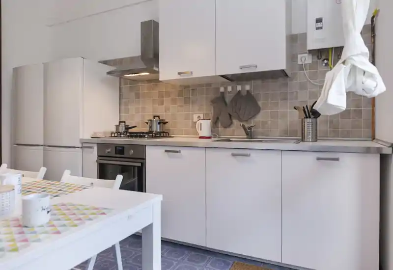 Bright, tidy kitchenette with a gas hob, oven and fridge, styled with placemats and mugs for a welcoming feel.