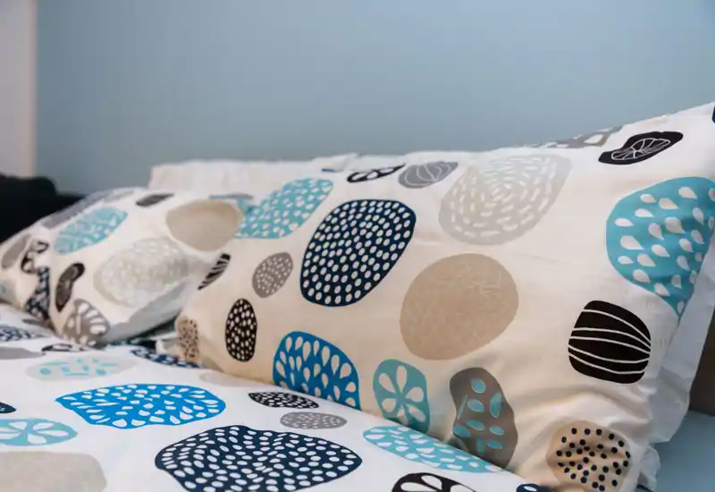Close-up of a bedroom showing patterned pillows and bedding in soft blue and neutral tones; crisp, inviting styling ideal for rental photos.