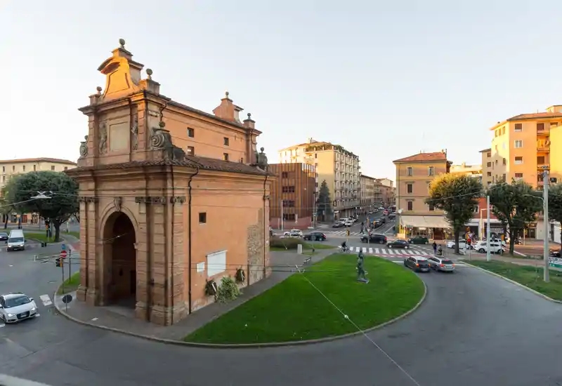 Scenic urban roundabout with a historic brick gate and surrounding apartment buildings, captured in warm golden-hour light. Ideal for showcasing location and street views.