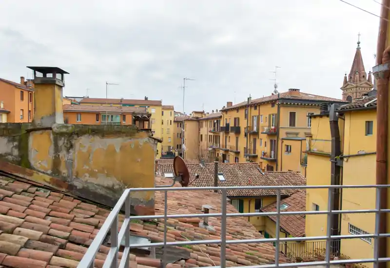 Balcon exposé donnant sur des toits en tuiles et des bâtiments ocre — idéal pour prendre un café le matin et profiter de la vue urbaine.