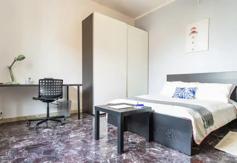 Bright, neatly staged bedroom with a double bed, bedside table and a desk area. Clean lines, decorative cushion and a soft throw create a welcoming atmosphere ideal for rental photos.