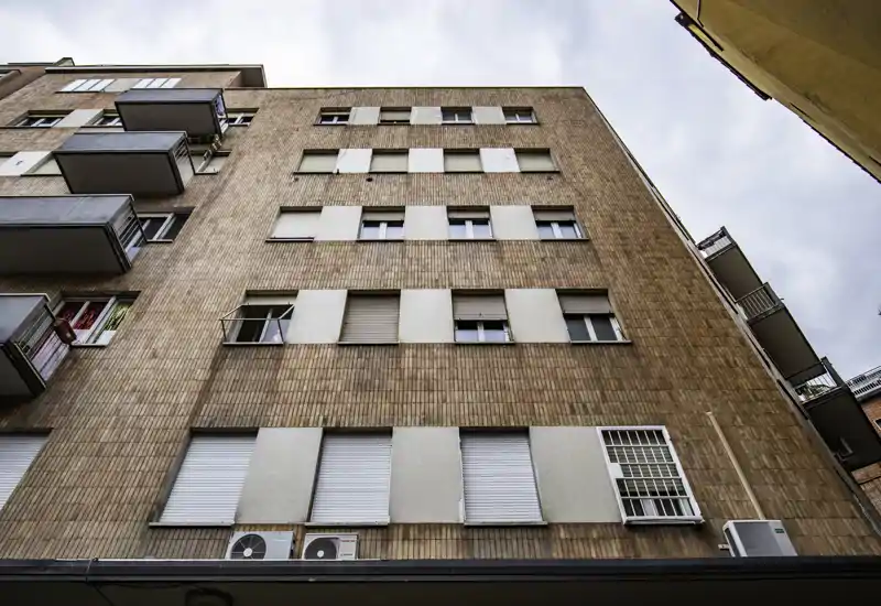 Exterior view of a multi-story residential building with brick façade, several windows and small balconies; suitable for showcasing the building’s exterior and street-level appeal.