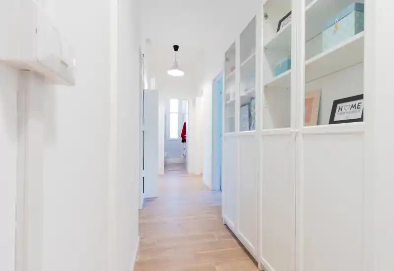 Bright, modern corridor with wood-effect flooring and built-in white storage cabinets—welcoming entrance hallway with clean lines and good natural light.