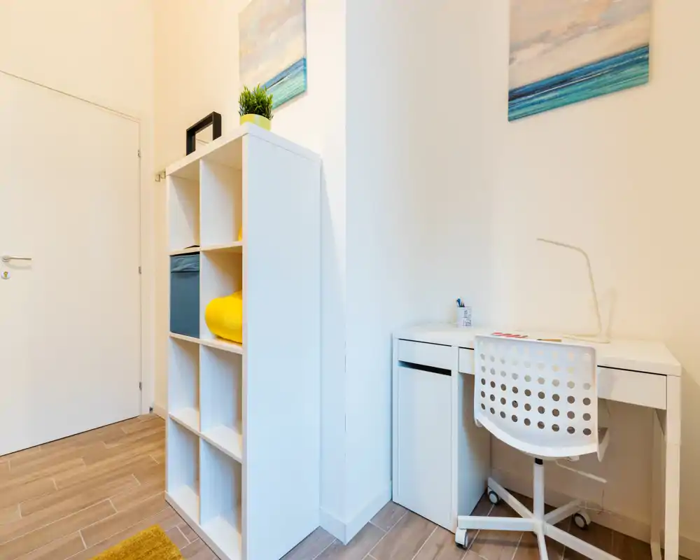 Petit espace de vie avec étagère blanche et bureau minimaliste — coin lumineux et moderne parfait pour le télétravail ou la lecture.