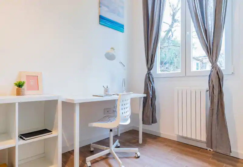 Bright, minimal workspace with a white desk, ergonomic chair and natural light from a window — a neat home office corner suitable for focused work.