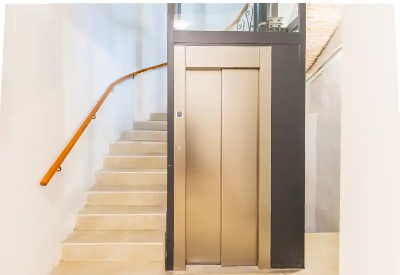 Bright entrance with an elevator and adjacent staircase, neutral tones and clean finishes — ideal for apartment access.