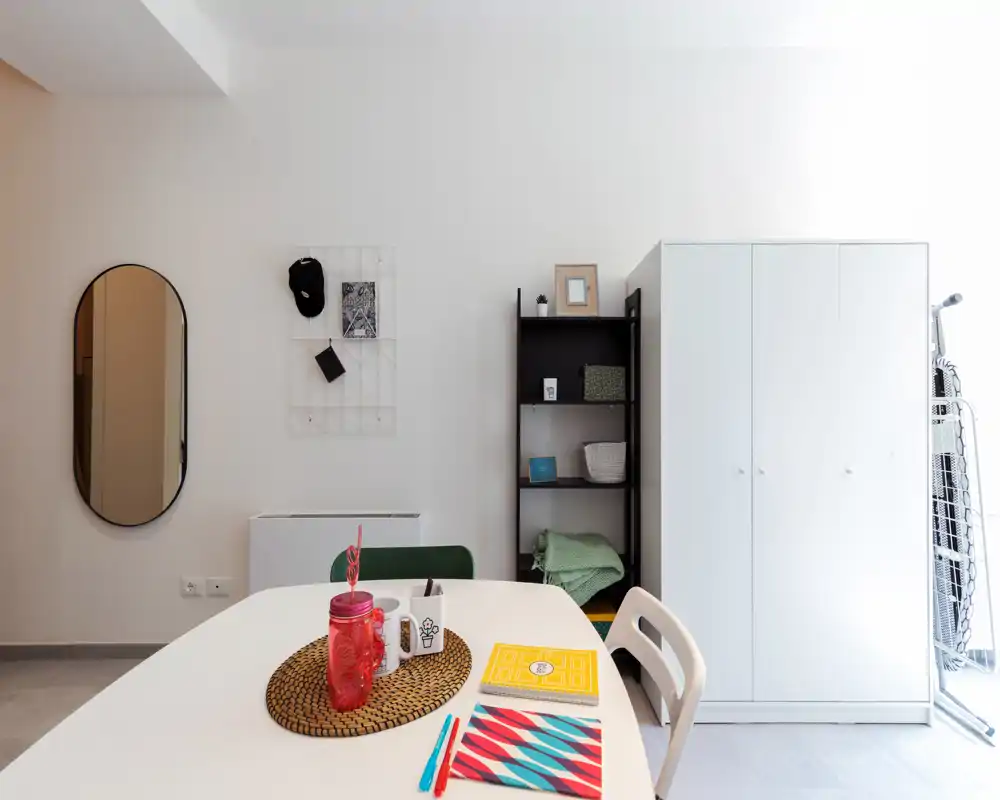 Bright, modern dining area with a white table set against a clean wall, decorative placemat and small accessories creating a welcoming, minimalist vibe.