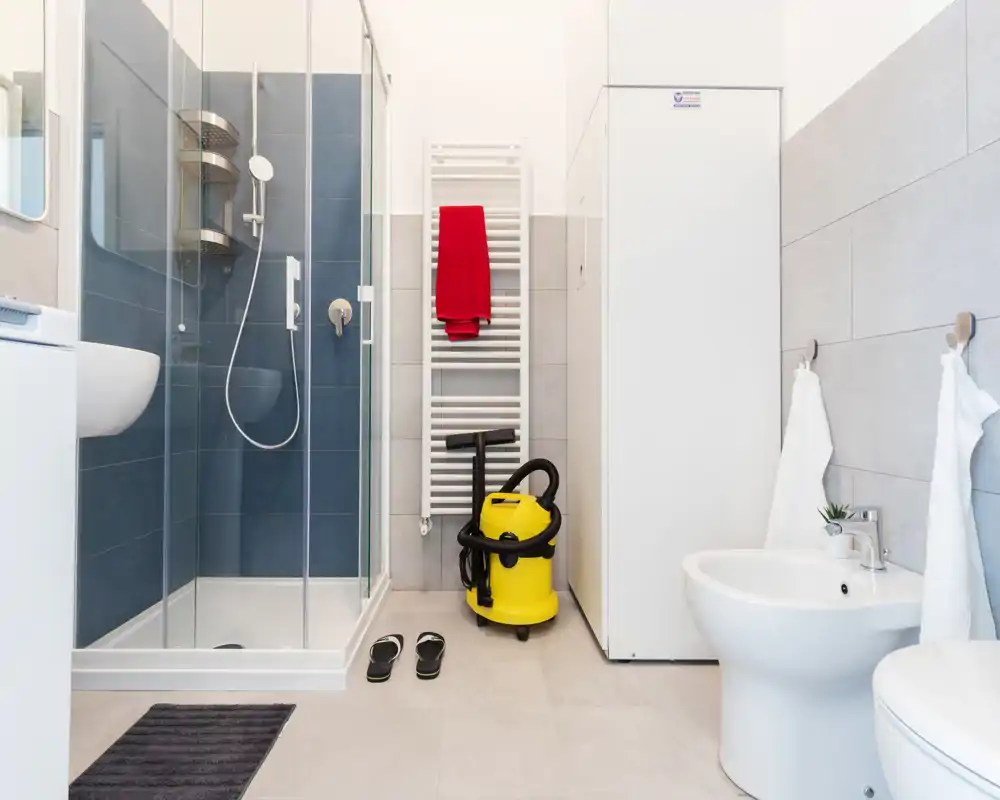 Bright modern bathroom with a glass shower enclosure, bidet and tidy fixtures; clean tiles and a towel radiator add functional detail.