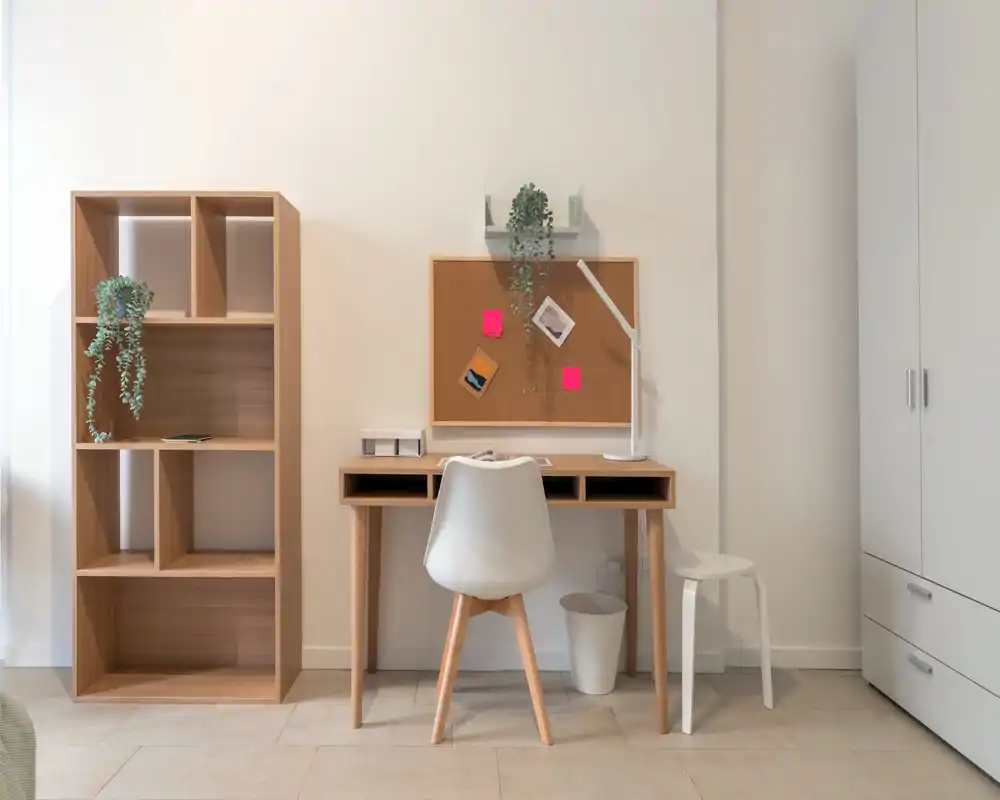 Angolo studio ordinato con scrivania in legno, sedia moderna, bacheca e scaffale — un angolo luminoso e minimal perfetto per studiare o lavorare da remoto.