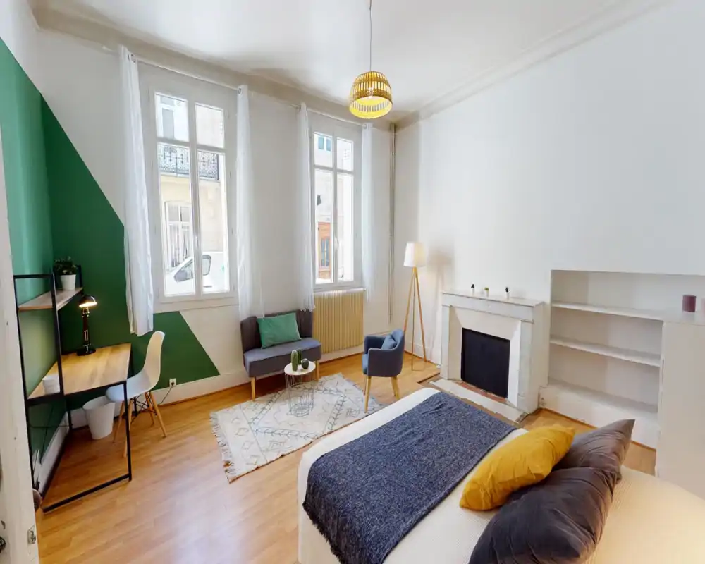 Camera da letto luminosa e stilosa con letto matrimoniale comodo, grandi finestre che assicurano luce naturale abbondante, tappeto accogliente e zona salotto, oltre a una scrivania vicino alla parete verde.