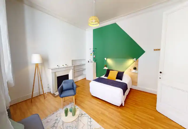 Camera da letto luminosa e di stile con letto matrimoniale davanti a una parete d'accento verde geometrica, tessili accoglienti e arredi contemporanei. Pavimento in legno caldo, mensole con piante e ottima luce naturale.