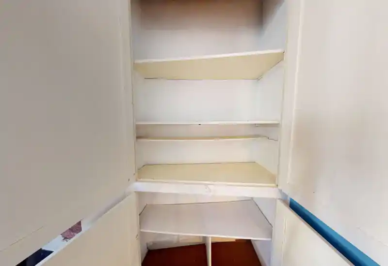 Primo piano di scaffalature/armadietto incassato; ripiani vuoti e pannelli interni visibili, ma la foto non consente di identificare il tipo di stanza (camera, cucina, bagno, ecc.).