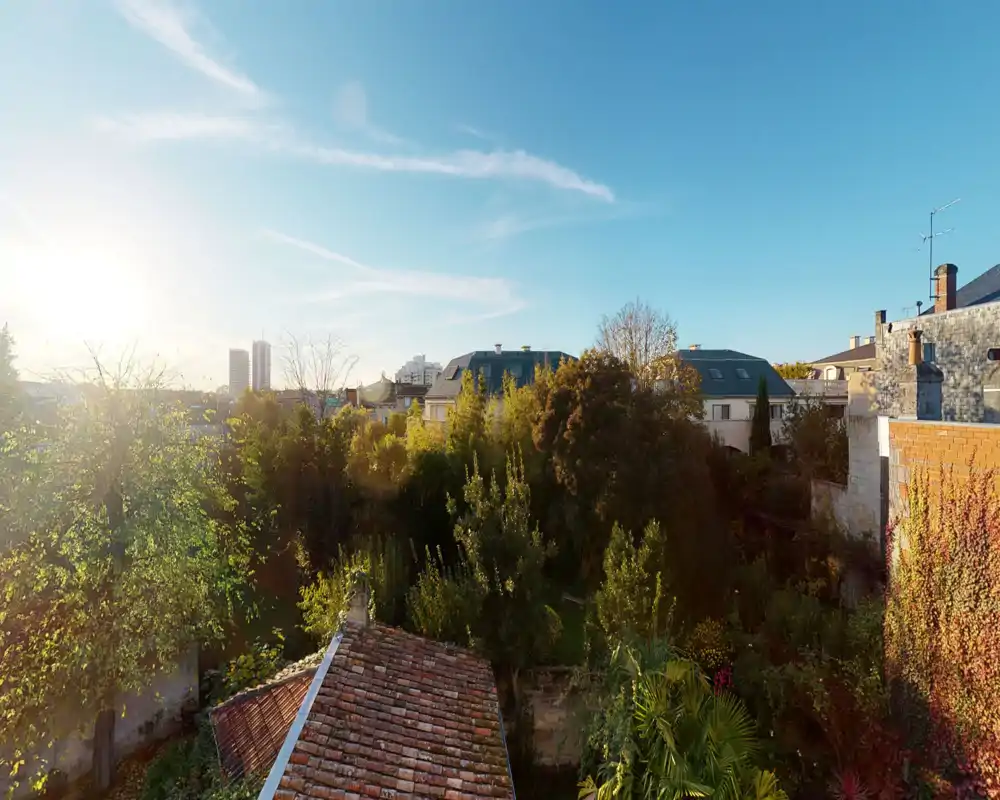 Sunny garden view with mature trees, neighboring rooftops and distant city skyline — ideal for listings highlighting outdoor green space and natural light.