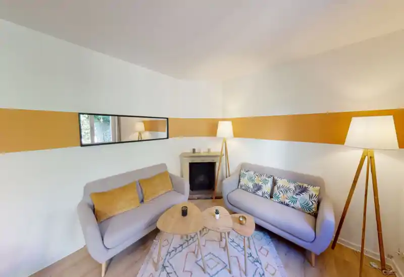 Soggiorno luminoso e accogliente con due divani moderni, cuscini decorati, tavolini a nido e lampade da terra calde — perfetto per rilassarsi o ricevere pochi ospiti.