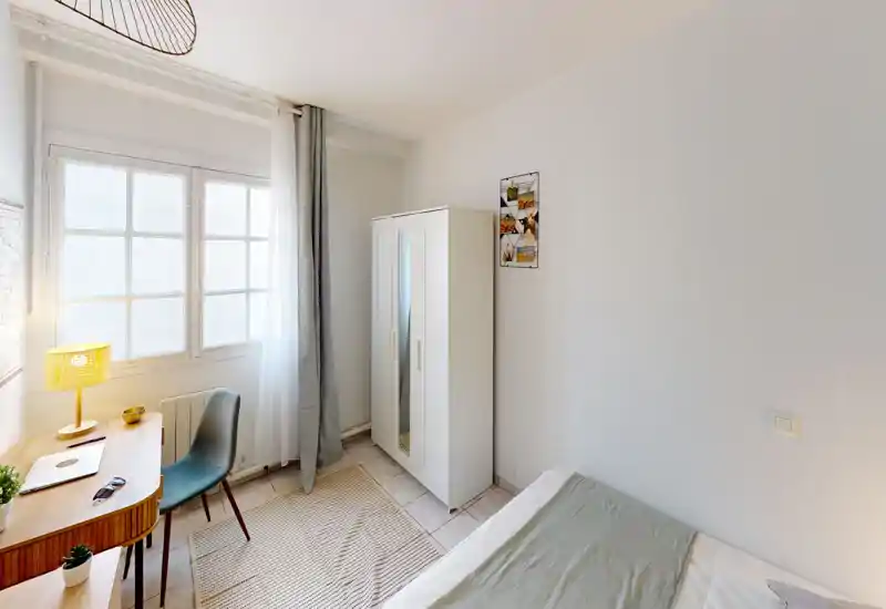 Chambre compacte et lumineuse avec lit simple, armoire et un petit bureau près de la fenêtre — idéale pour un étudiant ou une personne seule. La lumière naturelle et la décoration sobre donnent une atmosphère calme et accueillante.