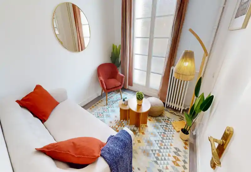 Soggiorno luminoso e curato con divano morbido, poltrona d'accento, tappeto decorato e illuminazione calda — uno spazio accogliente perfetto per rilassarsi.