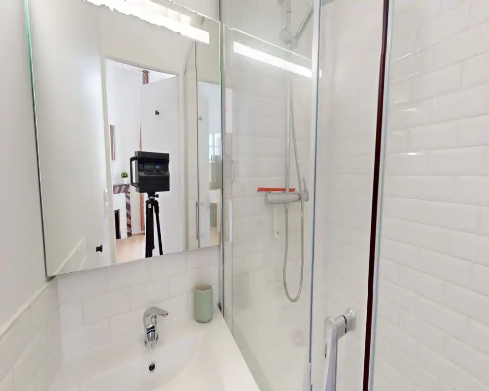 Bagno moderno e luminoso con piastrelle bianche effetto subway, box doccia in vetro e lavabo compatto con rubinetto cromato.