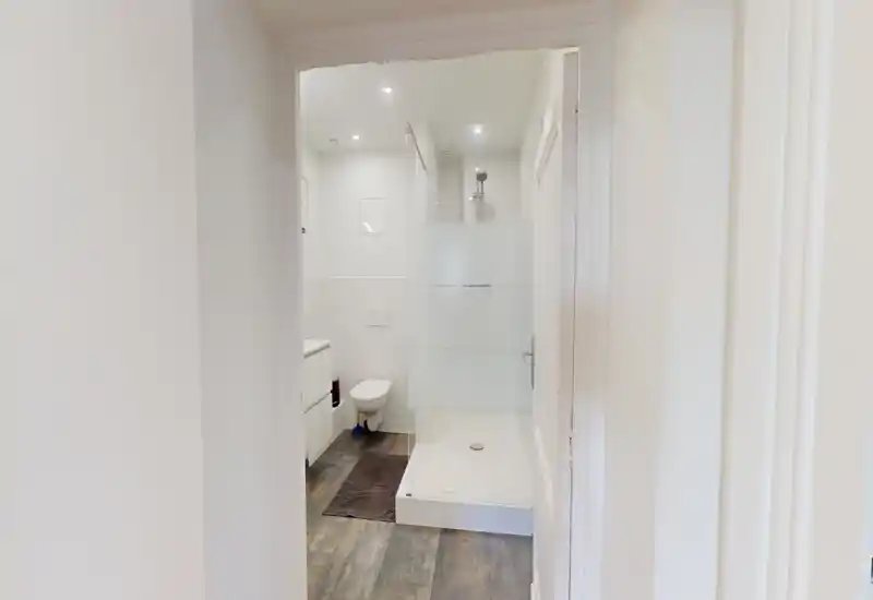 Bagno moderno e luminoso con doccia walk-in dotata di pannello in vetro smerigliato, wc sospeso e mobile lavabo compatto — stile pulito e minimalista con buona illuminazione.