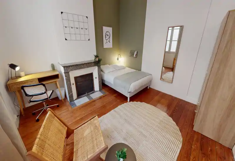 Camera luminosa e stilosa con letto matrimoniale vicino a una parete color oliva, pavimenti in legno, camino, scrivania e comodo angolo salotto — ideale per una o due persone.