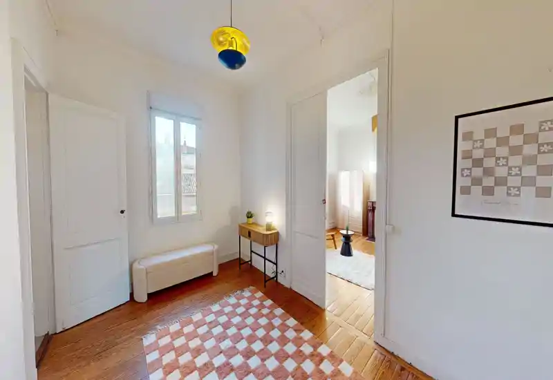 Zona giorno luminosa e minimale con pavimento in legno, tappeto a motivo, panca e consolle: ideale come area d'ingresso o transizione verso il soggiorno, molto luminosa.