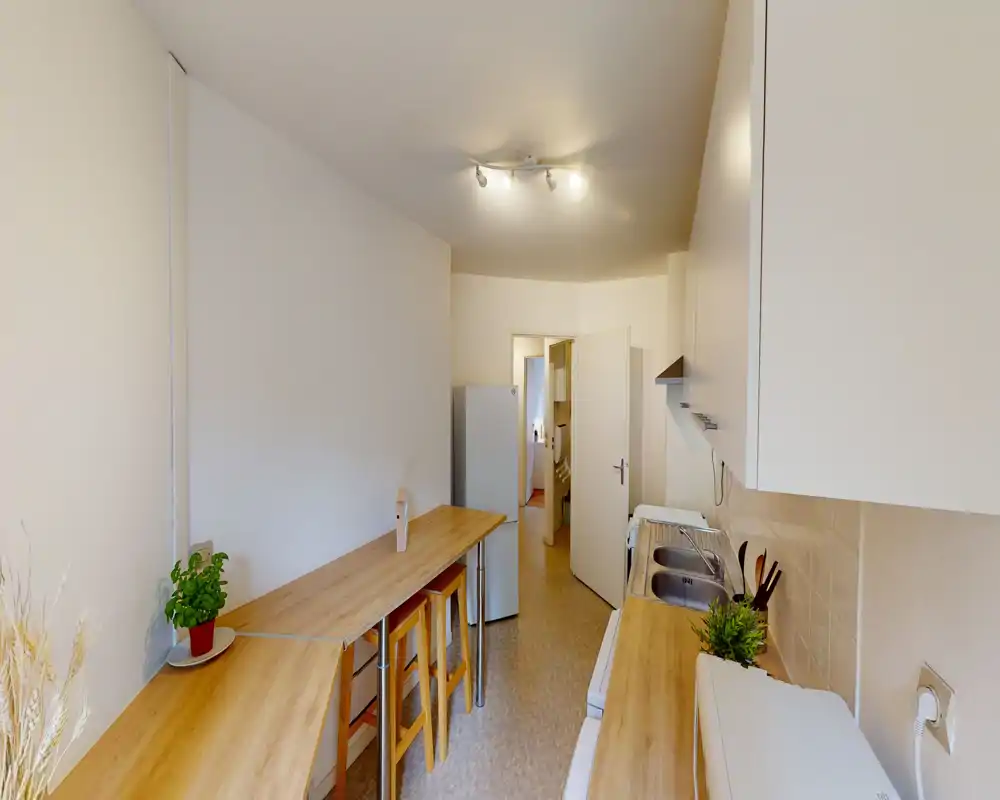 Bright galley kitchen with wooden countertops, breakfast bar seating and integrated sink — compact and well organized for everyday cooking.