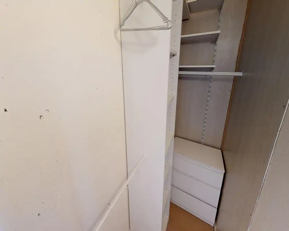 Petite penderie / dressing avec étagères intégrées, tiroirs et barres de suspension ; tons neutres et agencement pratique de rangement.