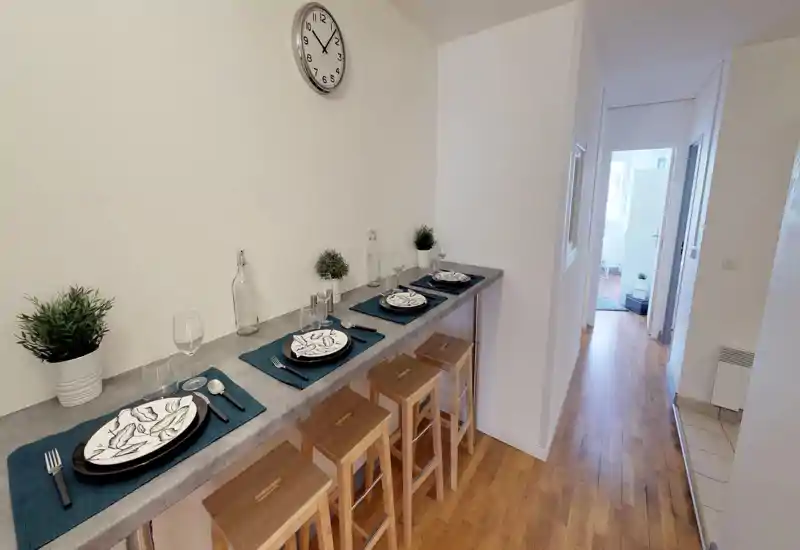 Stylish breakfast bar set for four with matching placemats, patterned plates and wooden stools — bright, tidy and ready for guests.