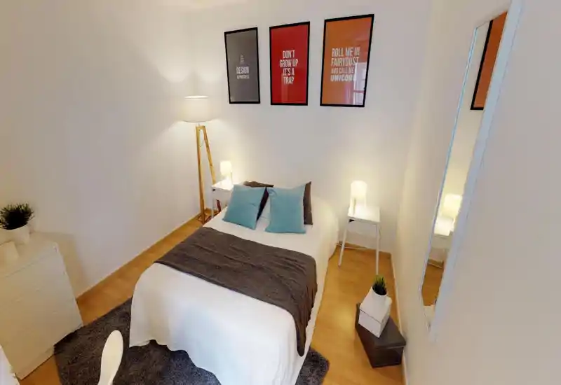 Bright, neatly styled bedroom with a centrally placed double bed, bedside tables and warm lighting. Soft textiles and framed wall art give the room a welcoming, contemporary feel.