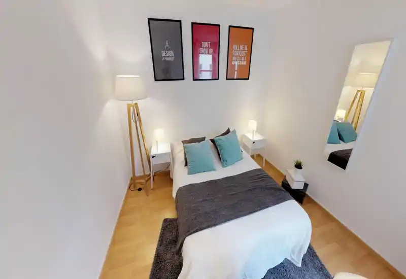 Bright, neatly staged bedroom with a central double bed, bedside tables and lamps, decorative cushions and a full-length mirror—ideal for rental photos.