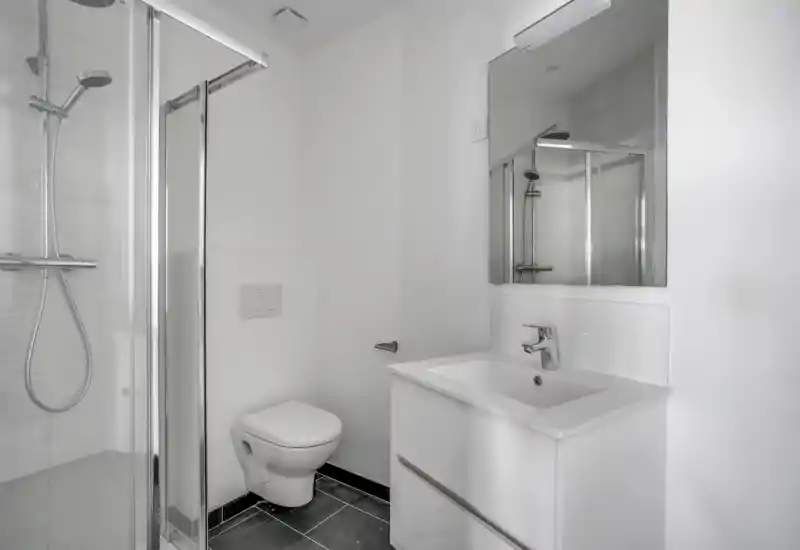 Bagno moderno e luminoso con box doccia in vetro, water sospeso e mobile lavabo bianco con specchio — design pulito e minimalista.