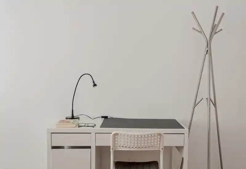 Entrée minimaliste avec un bureau console blanc épuré, une petite lampe de lecture, une chaise et un porte-manteau moderne — lumineux, net et élégant pour une première impression accueillante.